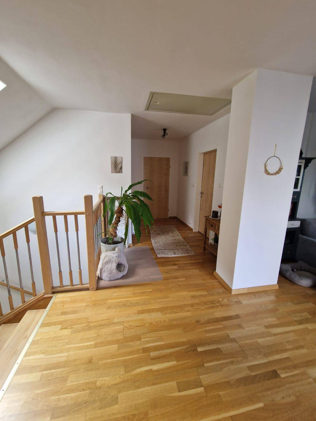 Heller Flur im Dachgeschoss mit Holztreppe, Parkettboden und Dachfenstern.