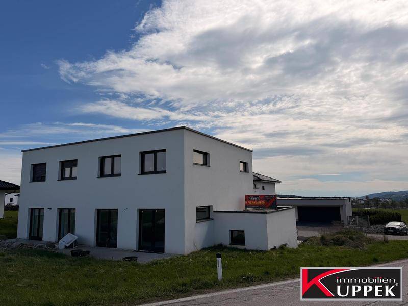 Rückansicht eines modernen Hauses mit großen Fenstern und Zugang zum Gartenbereich.