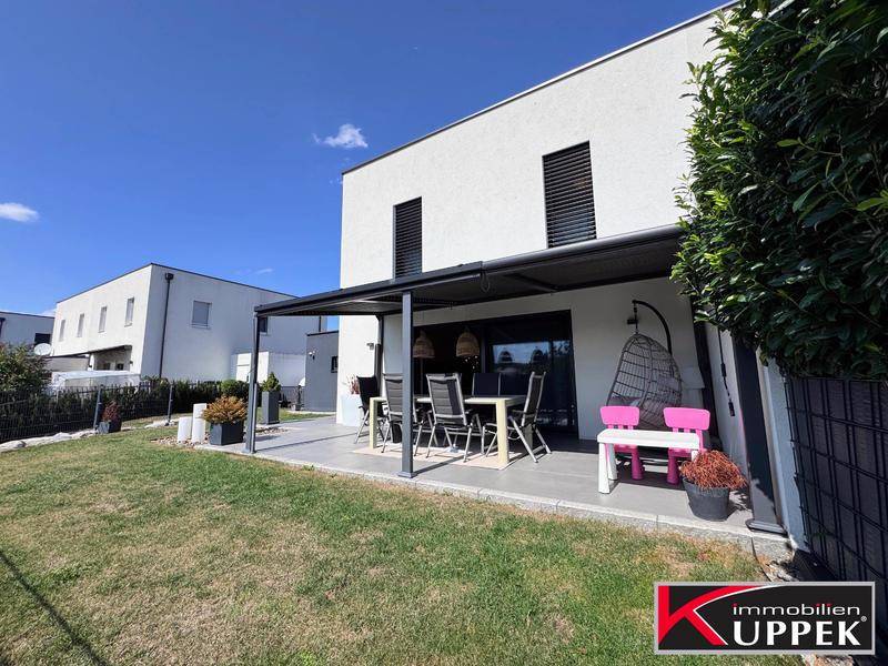 Geräumige Terrasse mit Esstisch und Lounge-Möbeln, umgeben von grünem Rasen.