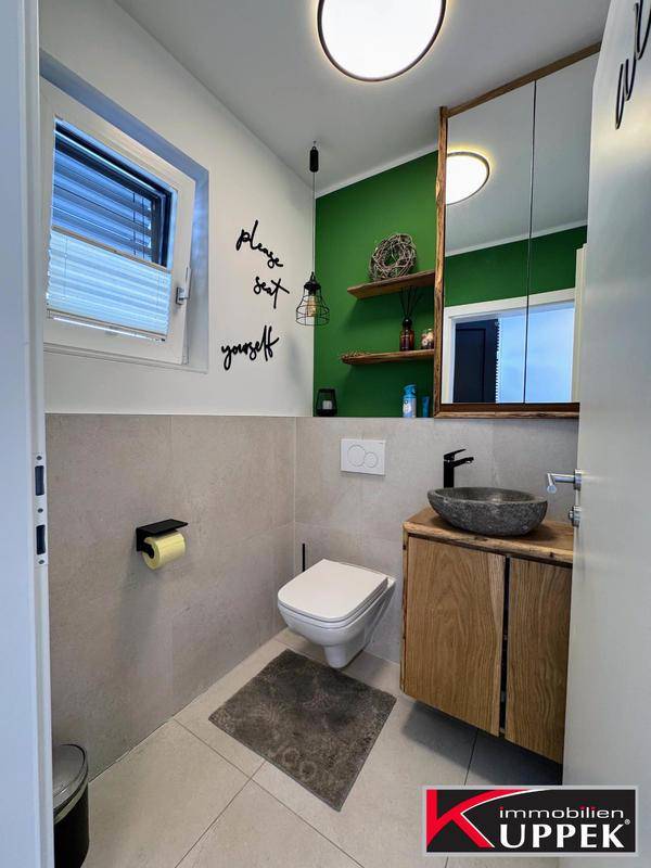 Modernes Gäste-WC mit grüner Akzentwand, Fenster und stilvollem Waschbecken.