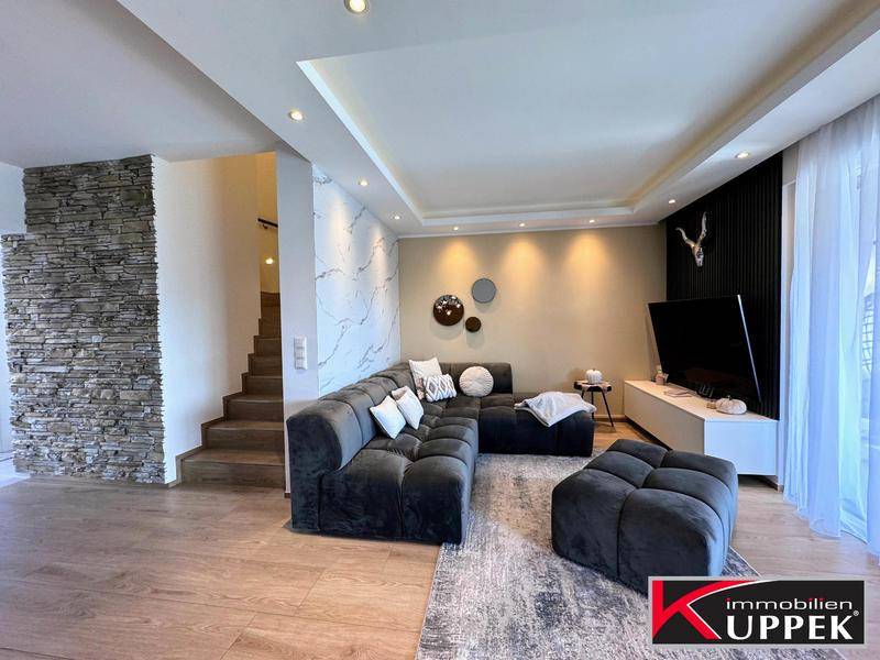 Gemütliches Wohnzimmer mit großem Ecksofa, Holzboden und dekorativer Steinwand.