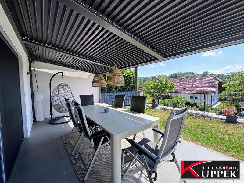 Überdachte Terrasse mit Esstisch und Hängesessel, ideal für entspannte Stunden im Freien.