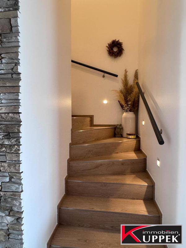 Elegante Holztreppe mit Steinwandakzent und indirekter Beleuchtung.