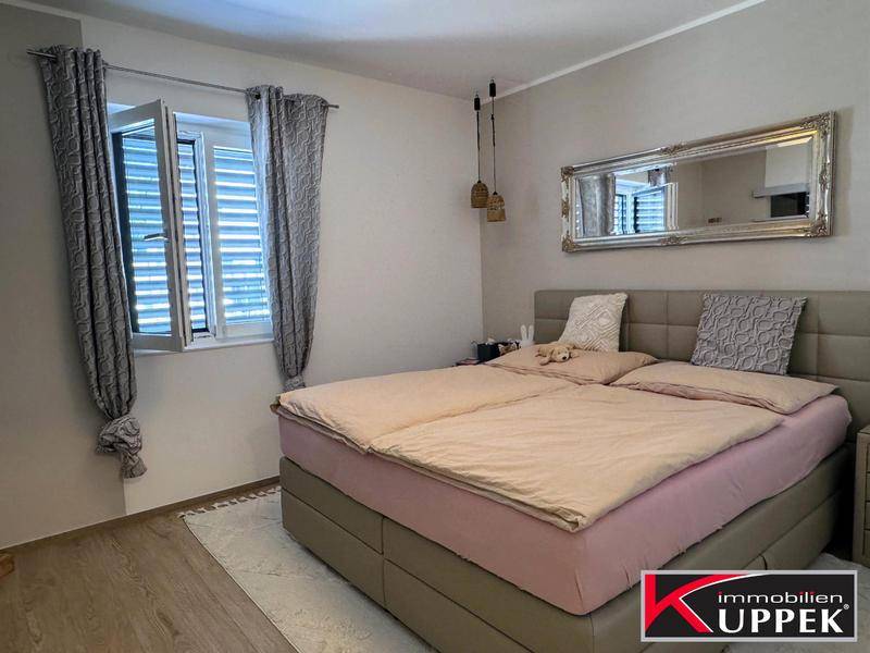 Gemütliches Schlafzimmer mit Doppelbett, Holzboden und großem Spiegel.
