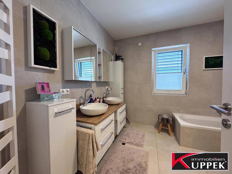 Modernes Badezimmer mit Doppelwaschbecken, Badewanne und Fenster.