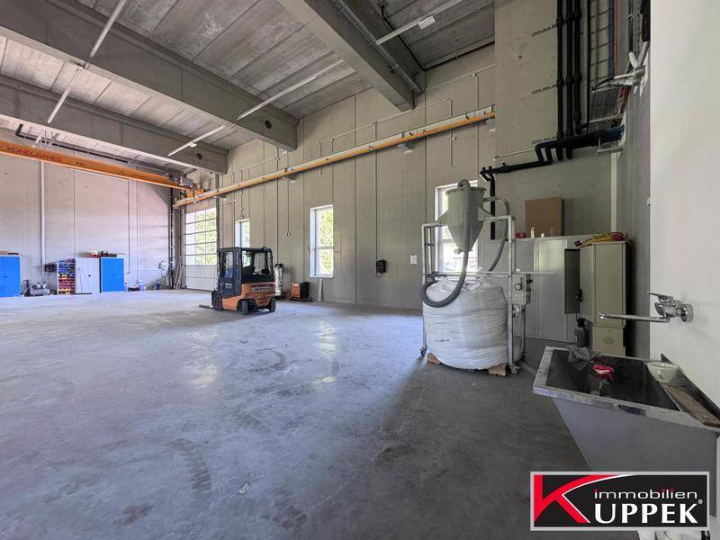 Weitläufige Lagerhalle mit Betonboden, hohen Decken und industrieller Ausstattung, bereit für den Betrieb.