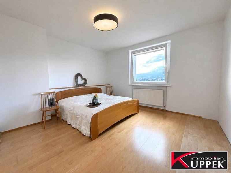 Schlafzimmer mit Holzbett, hellen Wänden und Fenster, das viel Tageslicht hereinlässt.