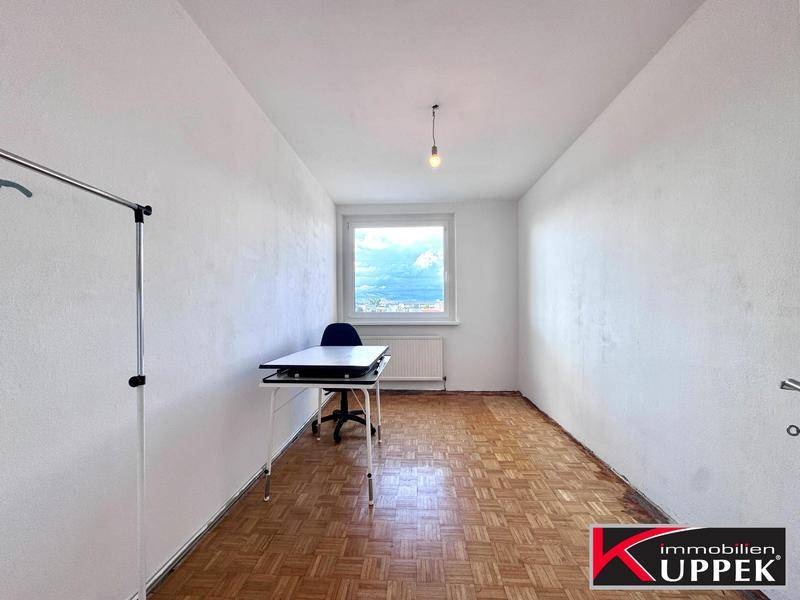 Helles Zimmer mit Parkettboden, Schreibtisch und Fenster, ideal als Arbeits- oder Gästezimmer.