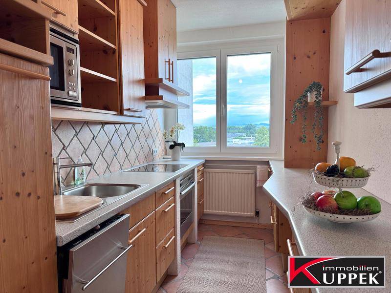 Funktionale Küche mit Holzschränken, gefliestem Spritzschutz und Fenster mit Ausblick.