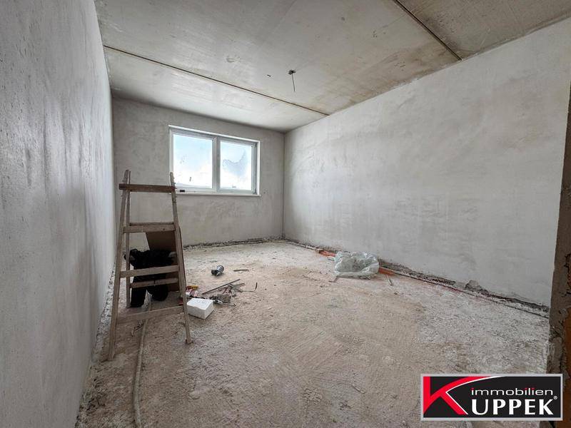 Rohbauzimmer mit einem Fenster und einer Leiter, bereit für den weiteren Ausbau.