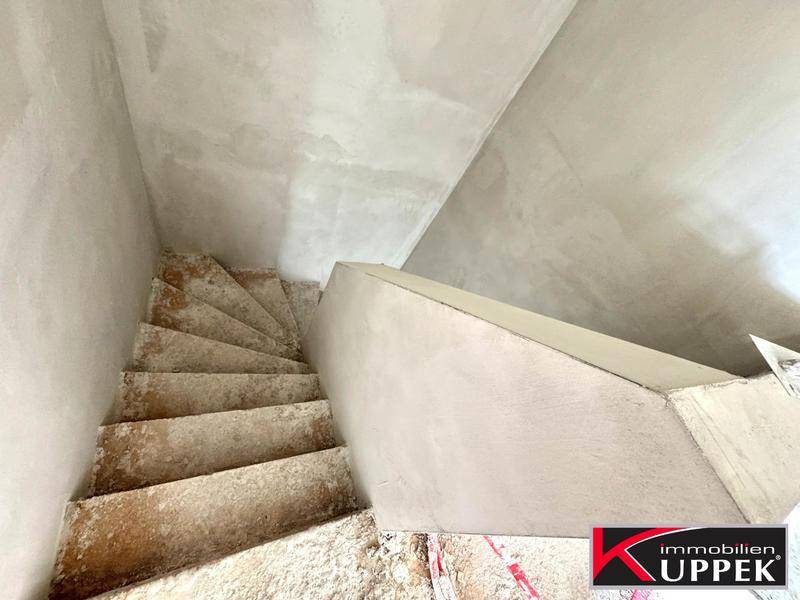 Unfertige Betontreppe im Rohbau, die in ein höheres Stockwerk führt.