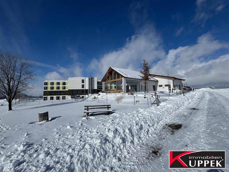 Gebäudekomplex in einer verschneiten Winterlandschaft unter blauem Himmel mit einigen Bäumen.