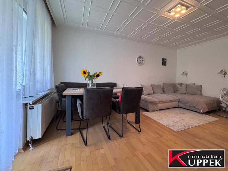 Geräumiger Wohn-Essbereich mit Esstisch, Sofa und Zugang zum Balkon, ideal für gesellige Abende.