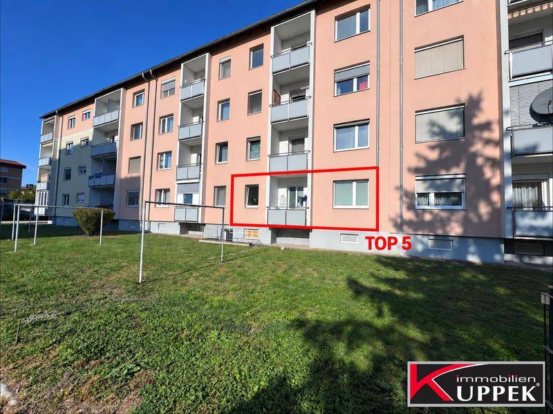 Ansicht des Mehrfamilienhauses von der Grünfläche aus, mit Blick auf die Balkone und die Fassade.