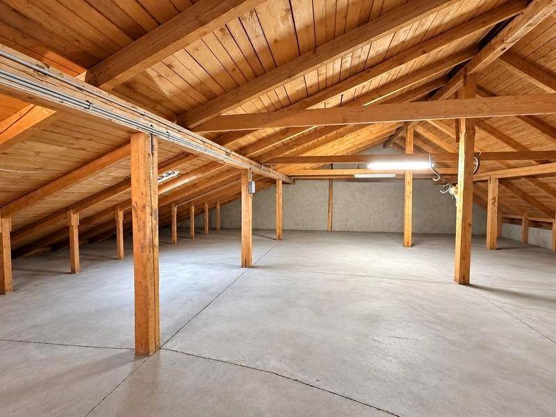 Geräumiger, ungenutzter Dachboden mit sichtbaren Holzbalken und Betonboden, bietet Ausbaupotenzial.