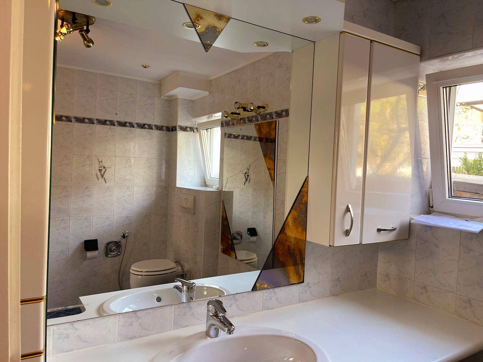 Badezimmer mit Einzelwaschbecken, Spiegelschrank und hellen Fliesen an den Wänden.
