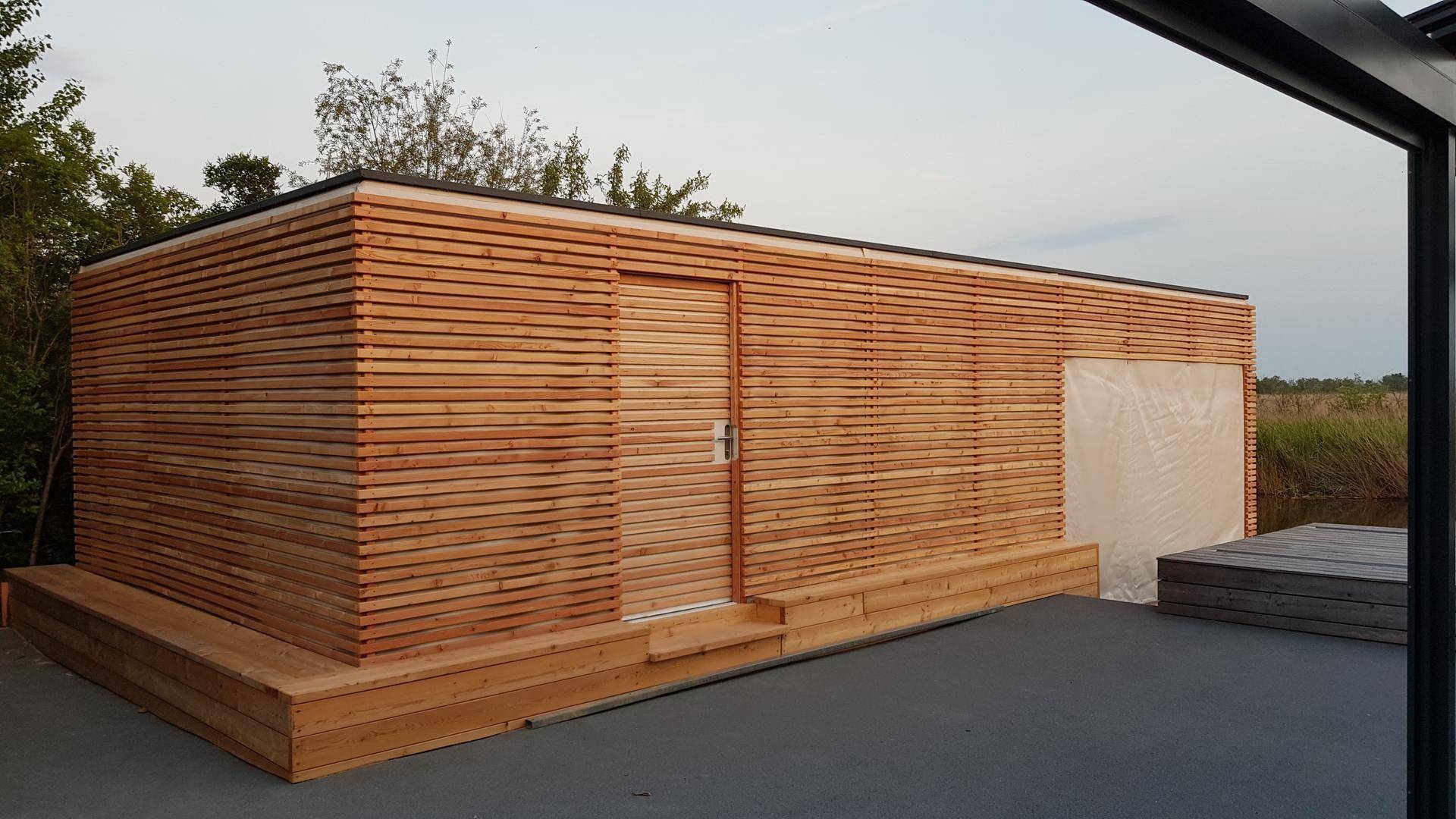 Modernes Holzgebäude mit horizontalen Lamellen, einer Tür und Stufen.