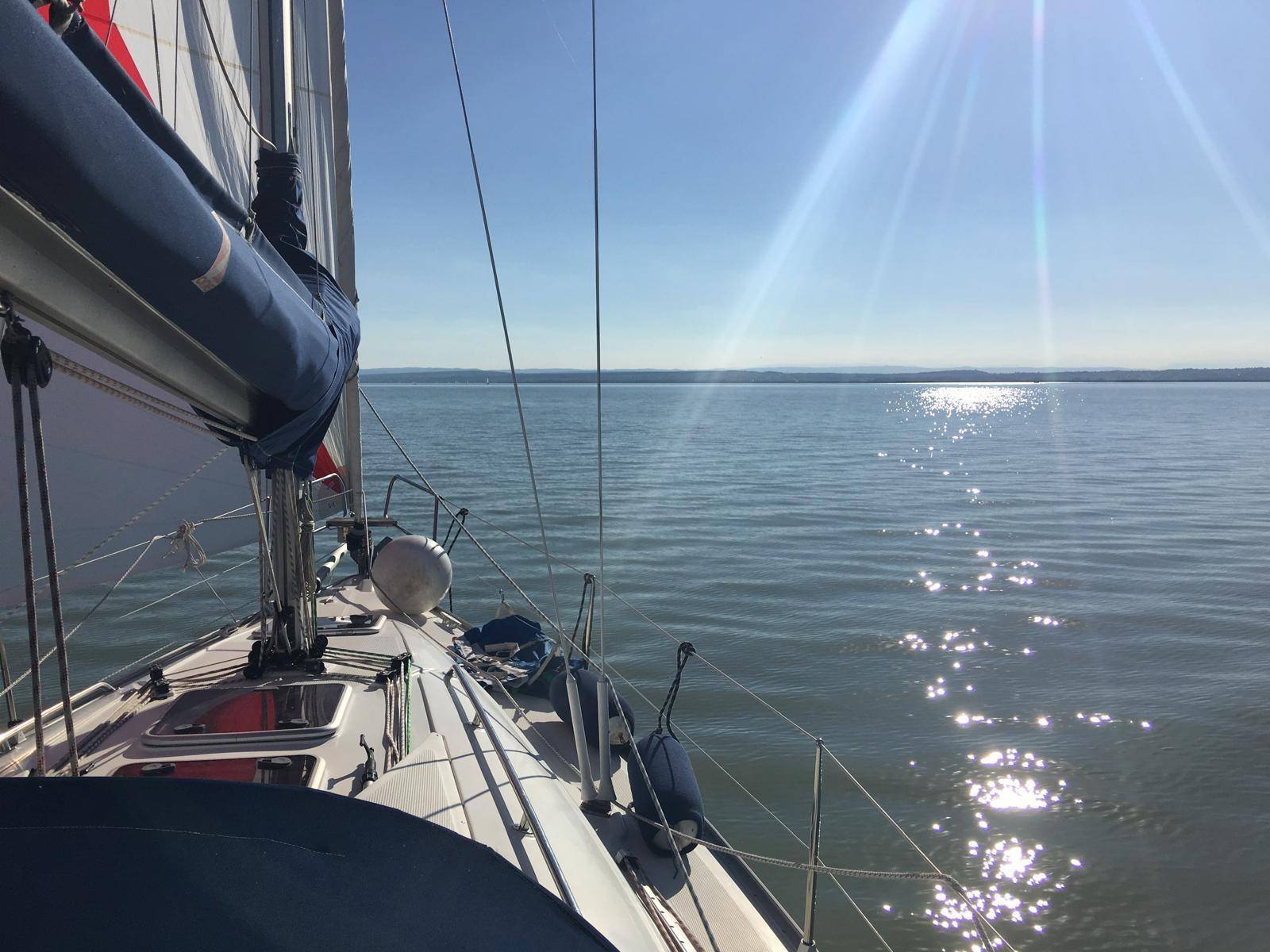 Sonniger Seeblick von einem Boot mit glitzerndem Wasser und entfernten Bergen.
