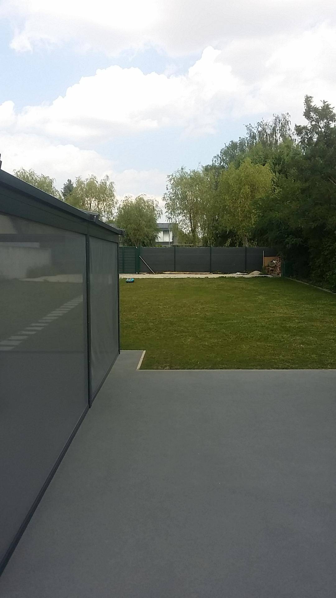 Geräumige Terrasse mit Blick auf einen grünen Garten und ein modernes Gebäude.