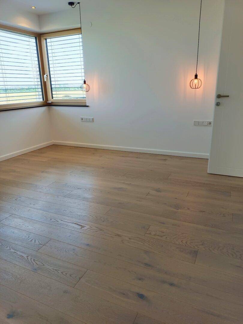 Helles Schlafzimmer mit Holzboden, großen Fenstern und modernen Pendelleuchten.