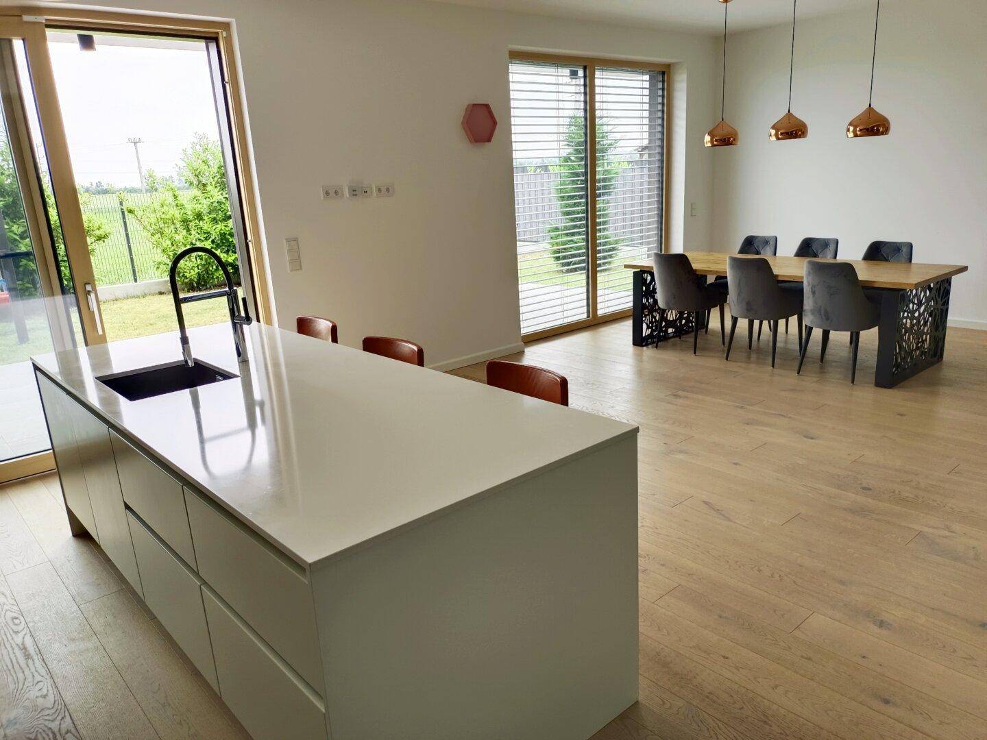Offener Wohn-Essbereich mit moderner Küche, Esstisch und Zugang zur Terrasse.