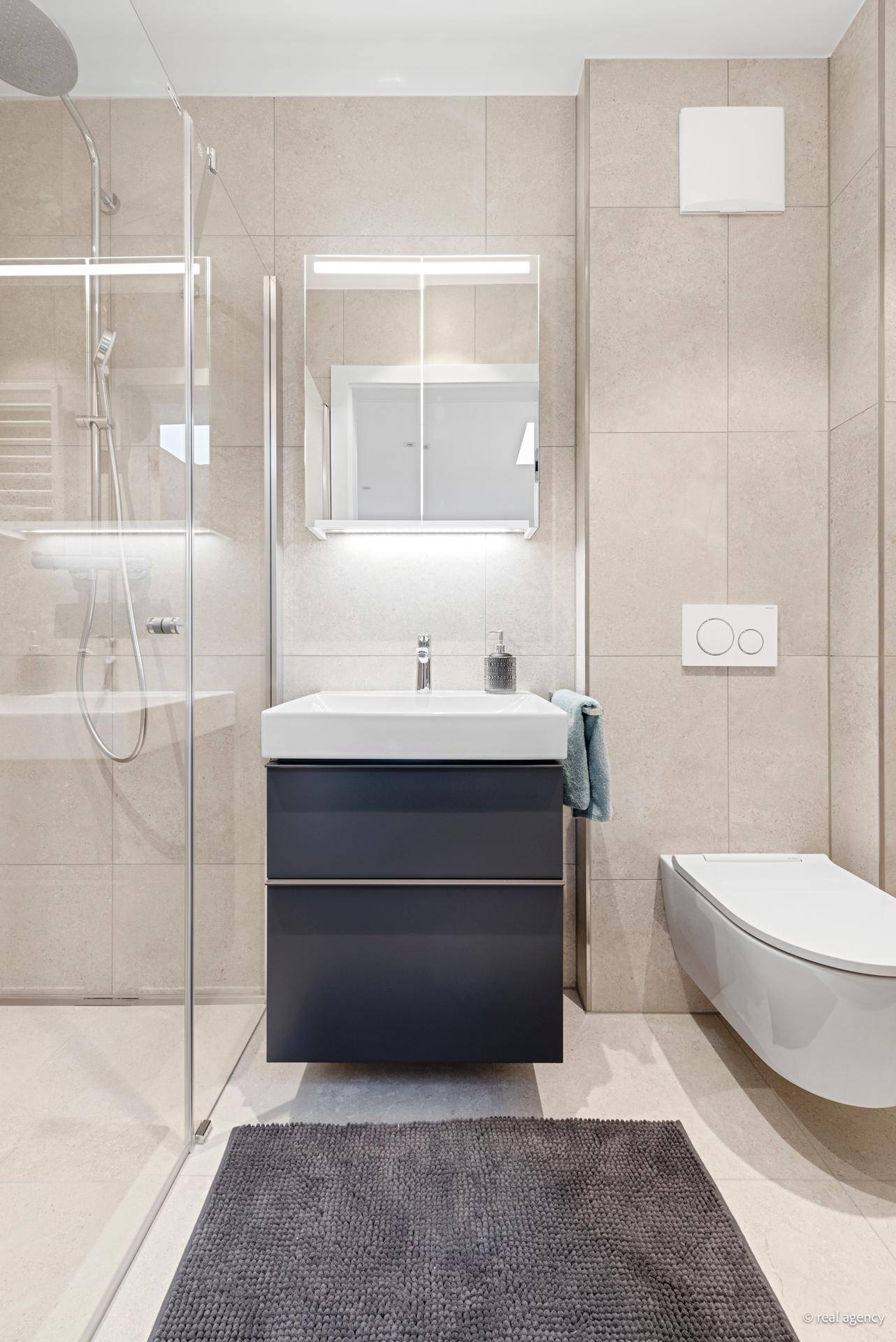 Modernes Gäste-WC mit Einzelwaschbecken, wandhängender Toilette und hellen Wandfliesen.
