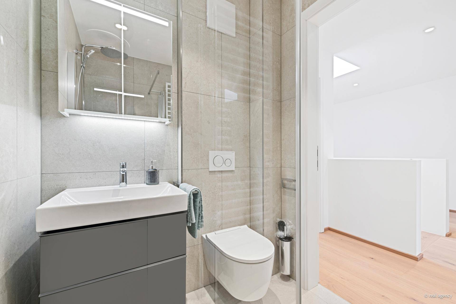 Modernes Gäste-WC mit Einzelwaschbecken, wandhängender Toilette und Duschbereich.