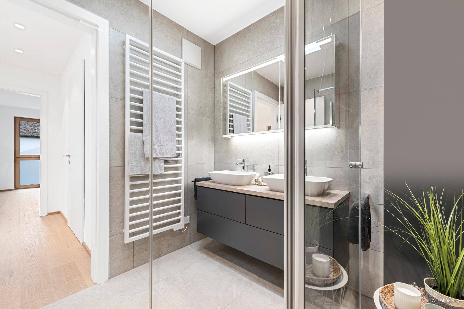 Elegantes Badezimmer mit zwei Waschbecken, begehbarer Dusche und beheiztem Handtuchhalter.