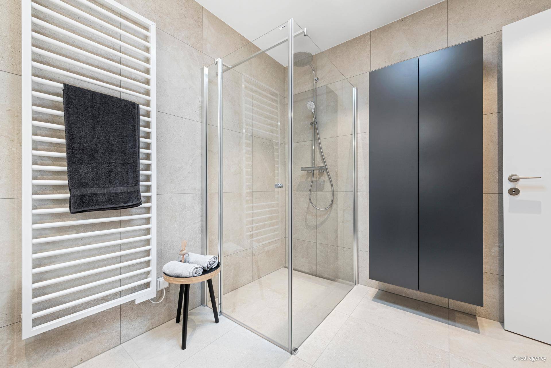 Modernes Badezimmer mit begehbarer Dusche, beheiztem Handtuchhalter und eleganten Fliesen.