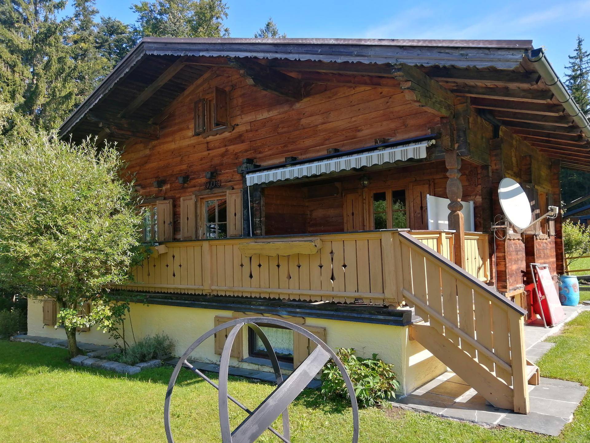 Rustikales Holzchalet mit traditioneller Architektur, umgeben von Grünflächen und Bäumen.