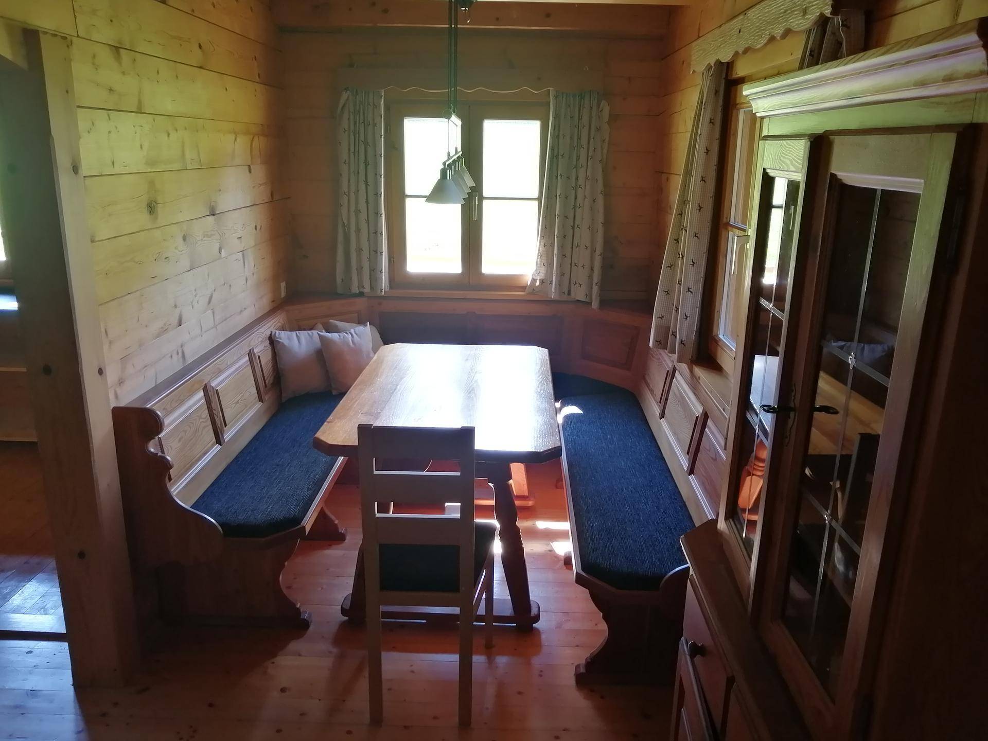 Traditioneller Essbereich mit Eckbank und Holztisch, umgeben von holzvertäfelten Wänden.