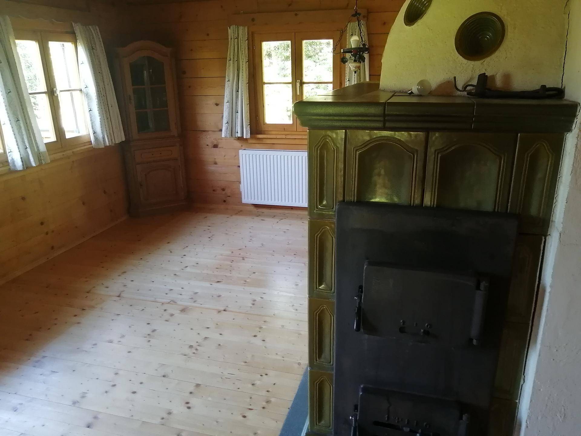 Gemütlicher Raum mit Holzböden und -wänden, ausgestattet mit einem traditionellen Kachelofen.