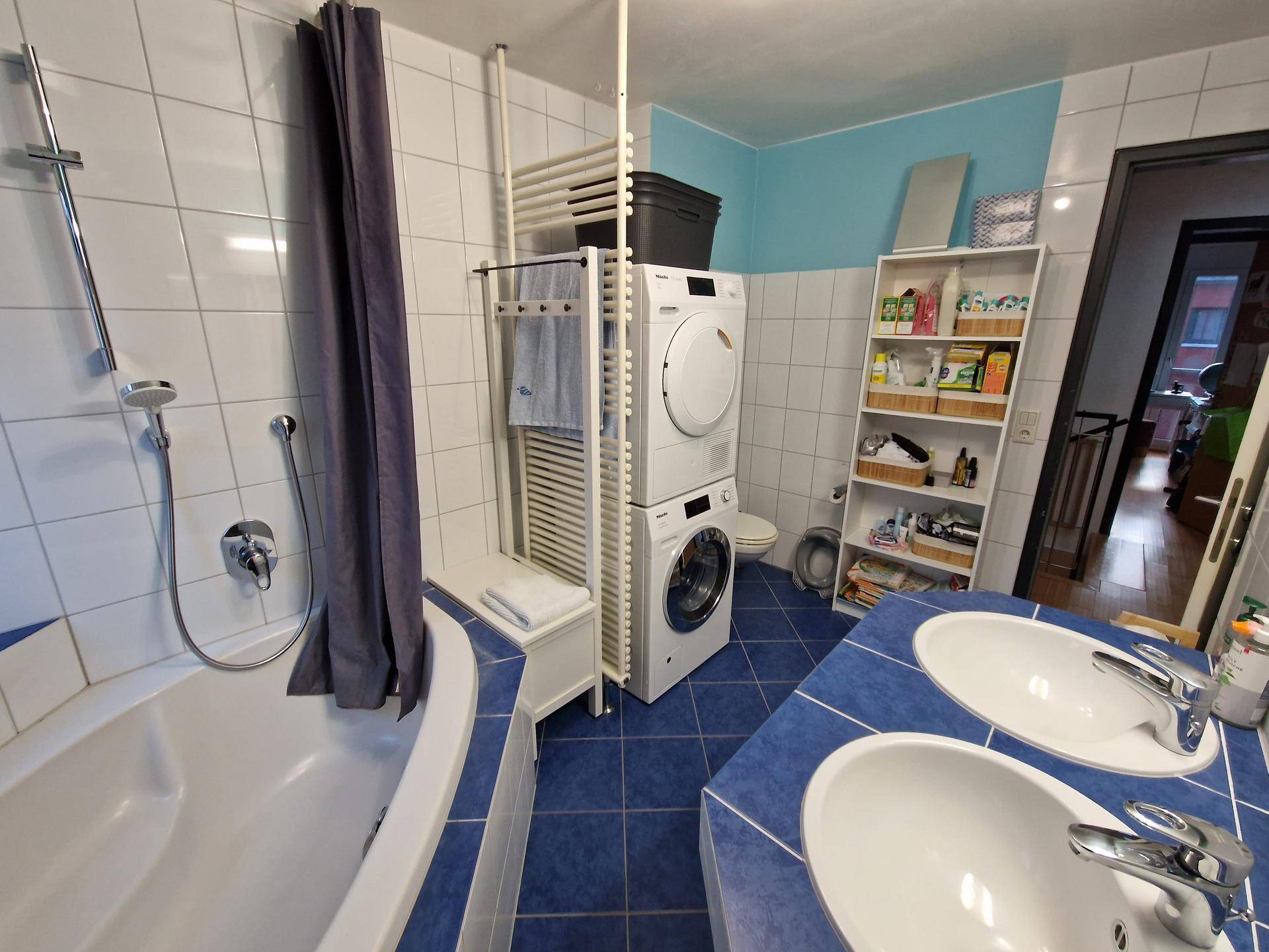 Geräumiges Badezimmer mit blauen Fliesen, Badewanne, Dusche und Doppelwaschbecken.
