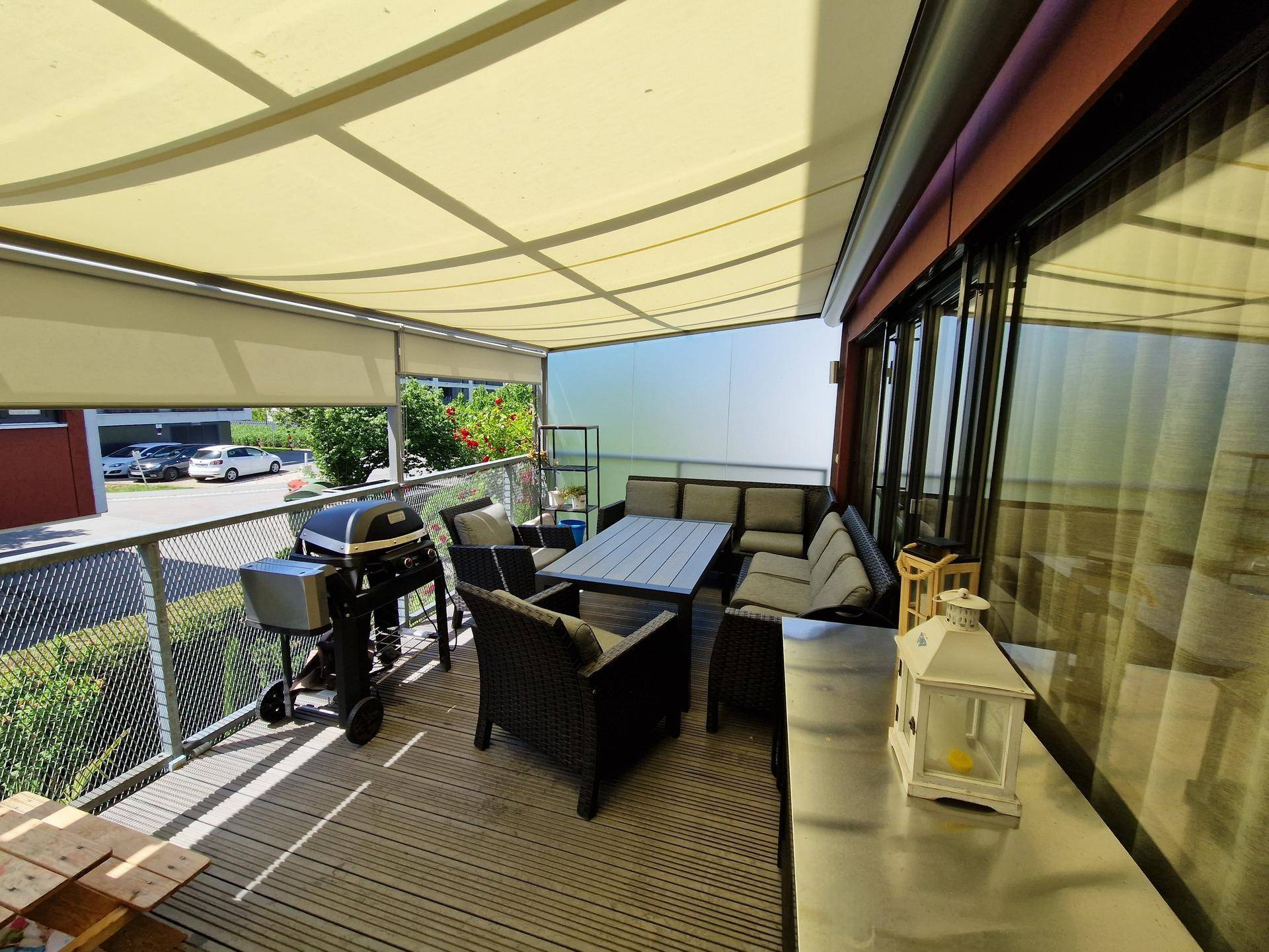 Geräumiger Balkon mit moderner Lounge-Sitzgruppe, Esstisch, Grill und ausziehbarer Sonnenmarkise.