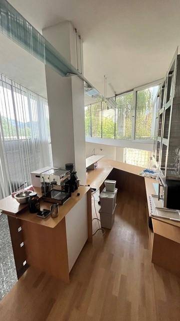 Heller Arbeitsbereich mit langen Schreibtischen, Büroausstattung und großen Fenstern für viel Tageslicht.