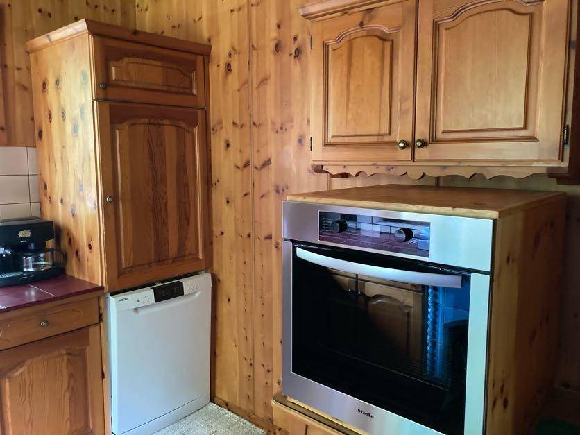 Einbauküche mit Holzschränken, integriertem Geschirrspüler und Backofen.