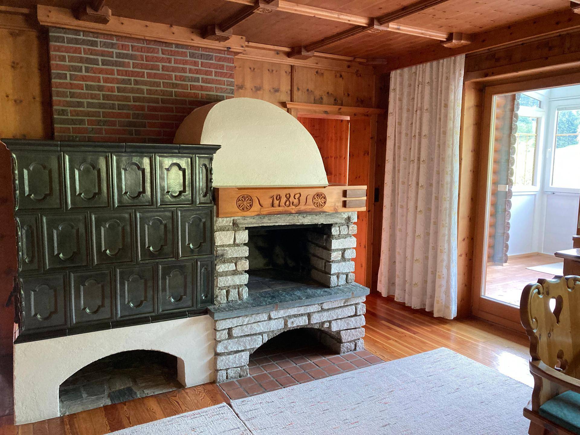 Wohnzimmer mit Kamin, Kachelofen und Holzboden im traditionellen Stil.