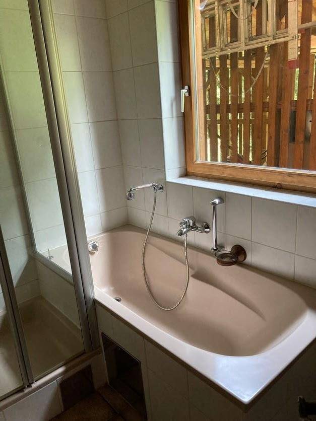 Badezimmer mit Badewanne, Duschvorrichtung und Fenster im traditionellen Stil.