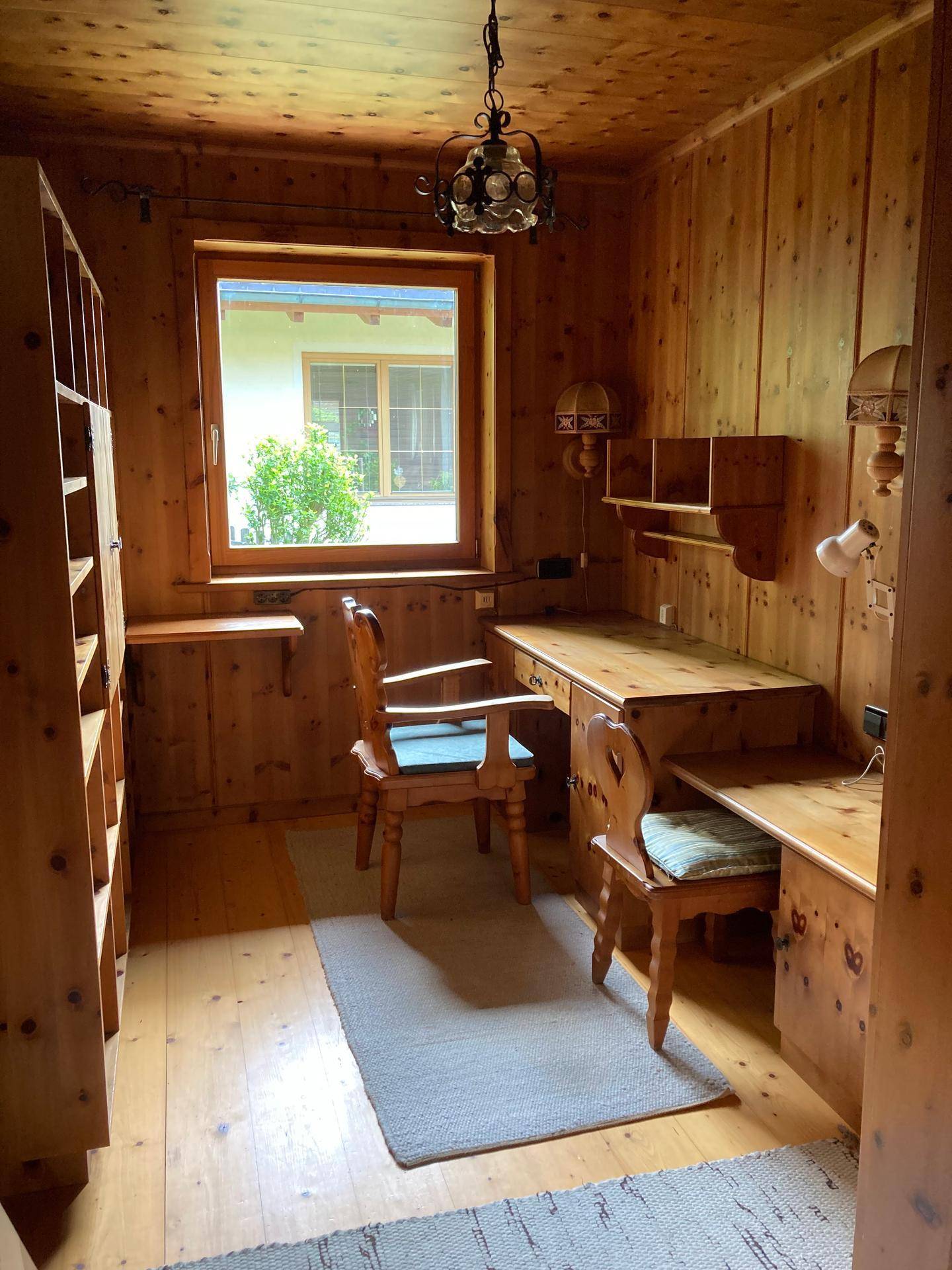 Arbeitszimmer mit Holzvertäfelung, Schreibtisch und Bücherregal im Landhausstil.