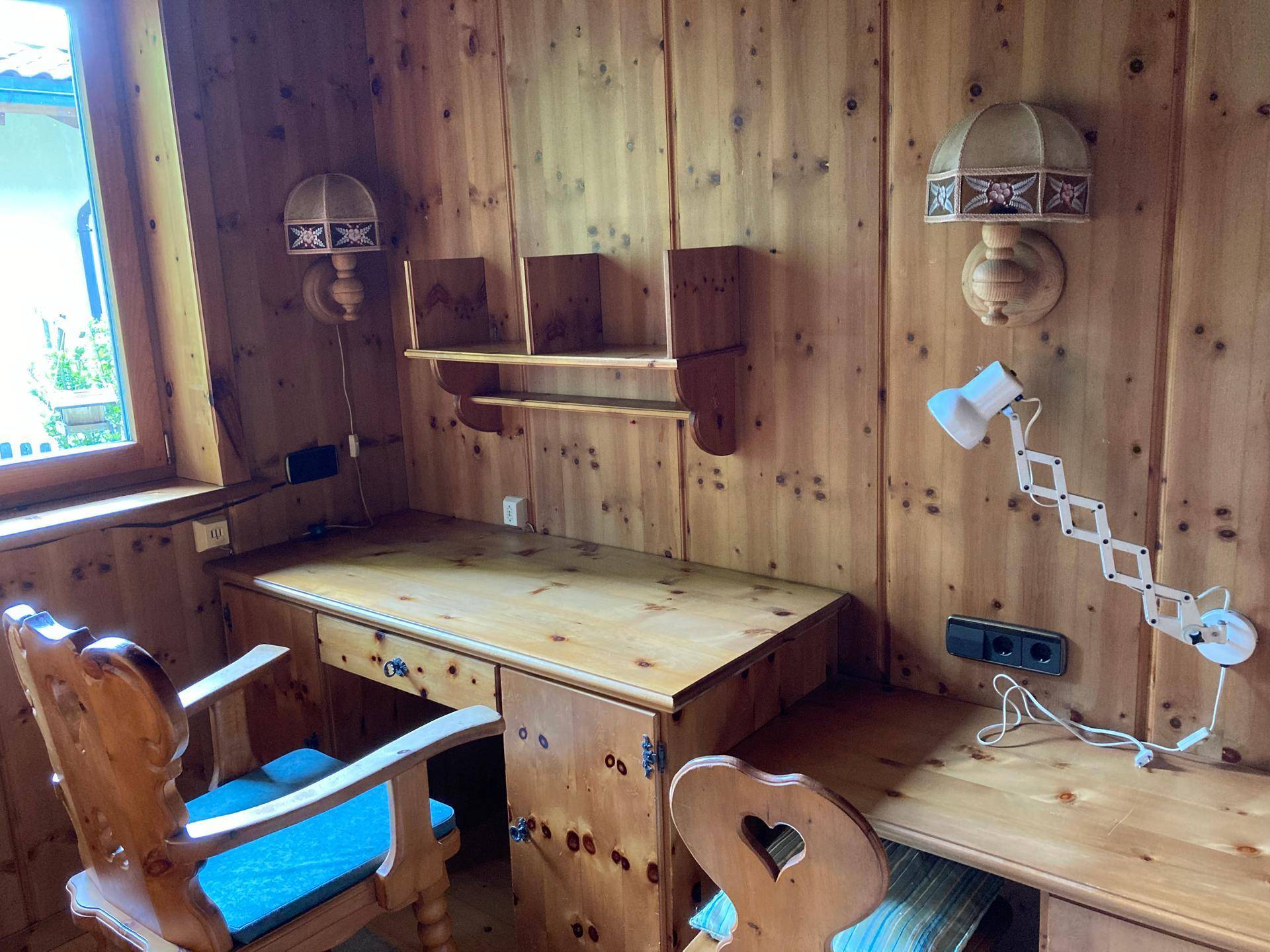 Detailansicht des Arbeitszimmers mit Holzschreibtisch und traditionellen Wandlampen.