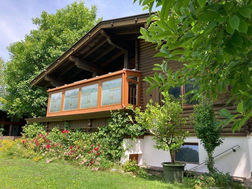 Charmantes Holzhaus mit üppiger Bepflanzung und blühenden Rosen im Sommer.