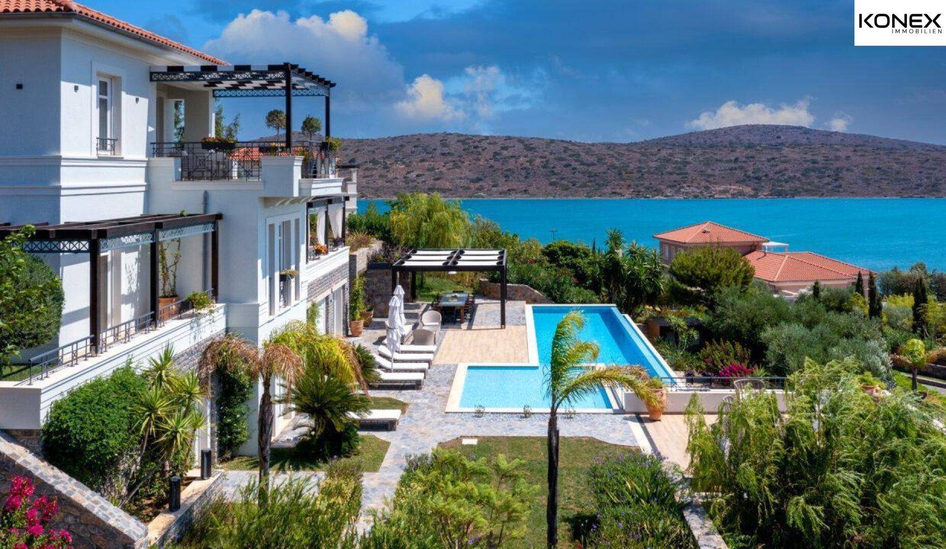 Elegante Villa mit großem Poolbereich und atemberaubendem Meerblick unter blauem Himmel.