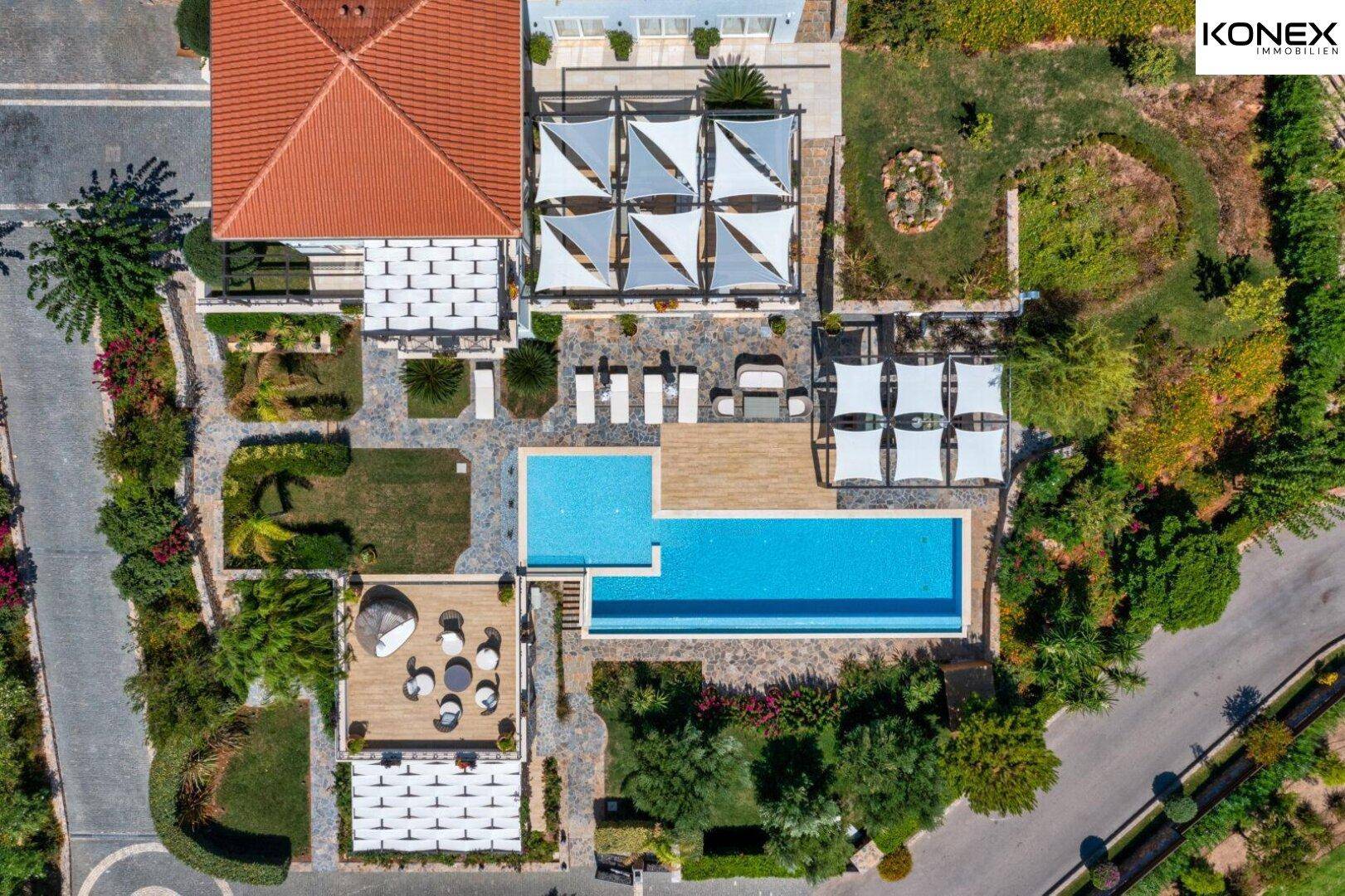 Vogelperspektive der luxuriösen Villa mit großem Pool, Sonnenterrassen und gepflegten Gärten.