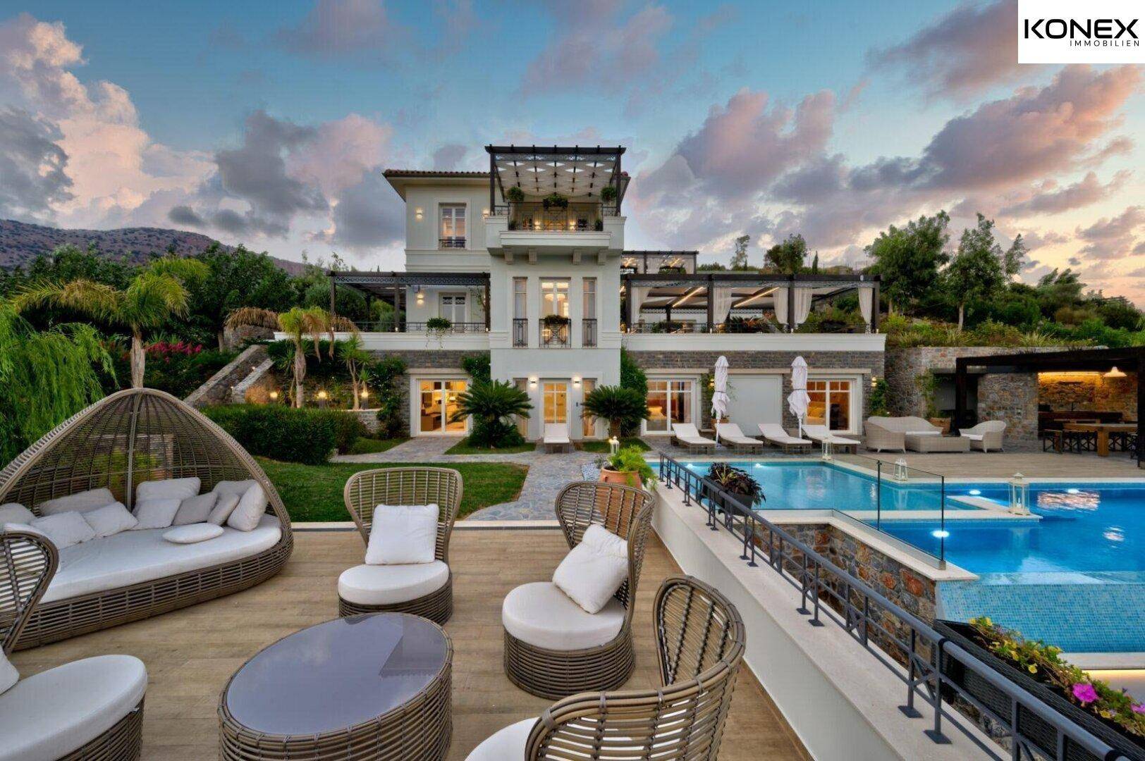 Geräumige Terrasse mit stilvollen Loungemöbeln und Blick auf den Pool und die Villa.
