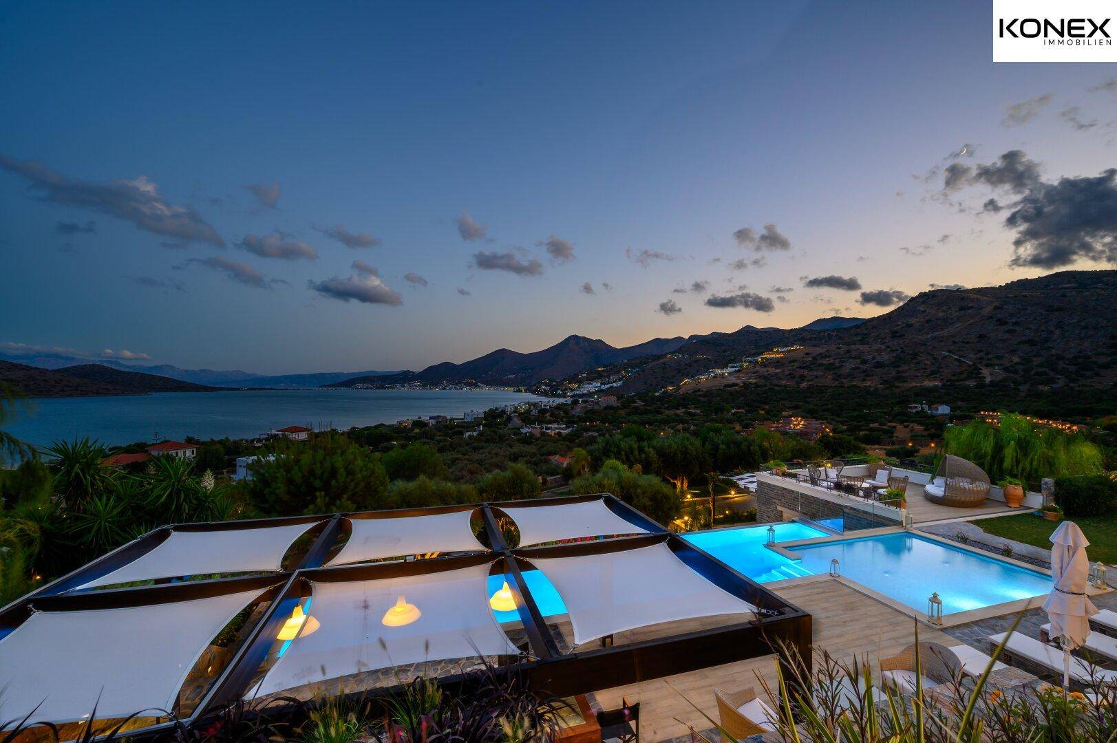 Abendliche Ansicht der beleuchteten Pool- und Terrassenbereiche mit weitem Blick auf die Bucht.