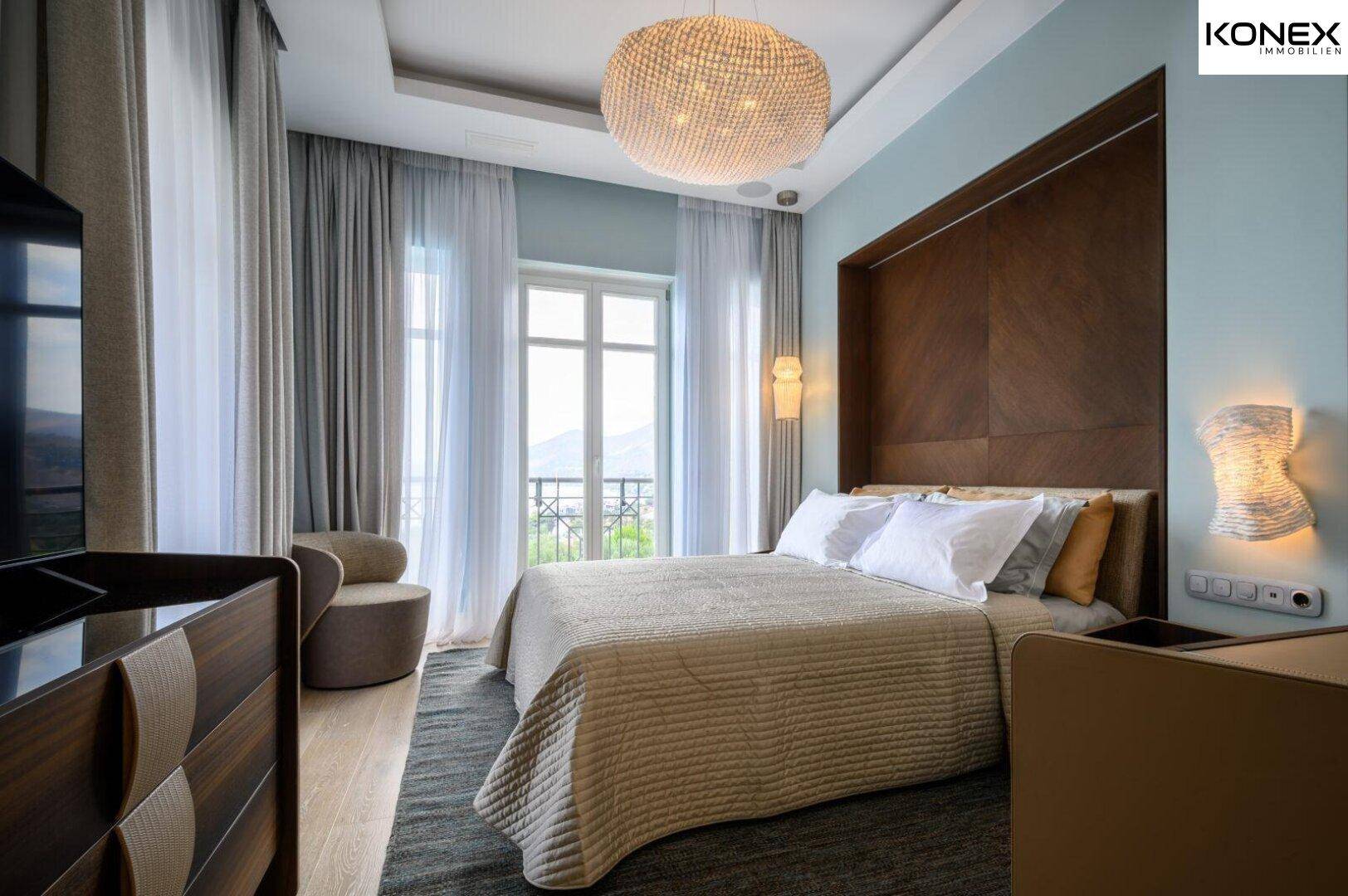 Elegantes Schlafzimmer mit Holzboden, großem Bett und Zugang zu einem französischen Balkon.