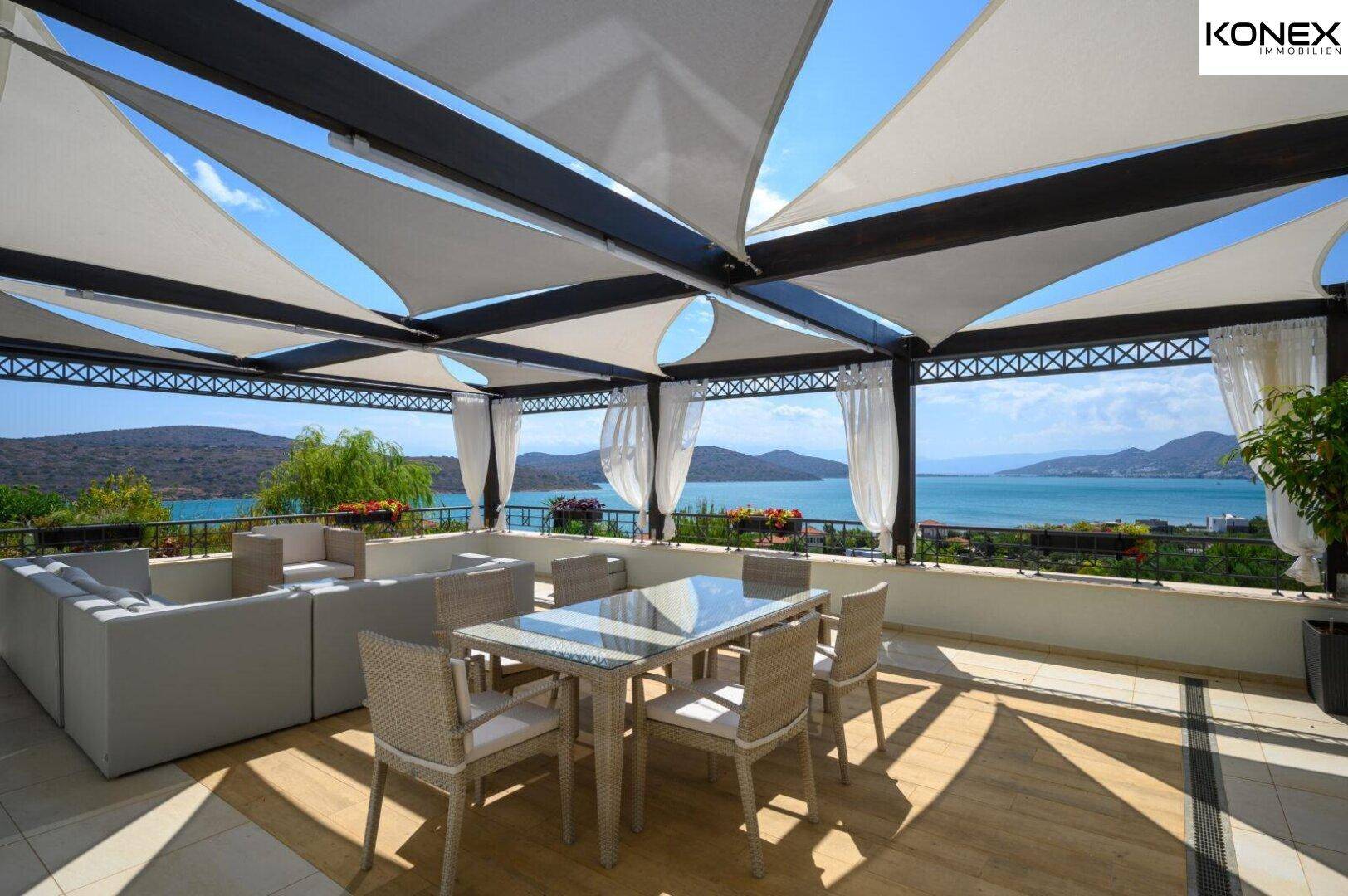 Überdachte Terrasse mit Ess- und Loungebereich, Meerblick und schattenspendenden Segeln.