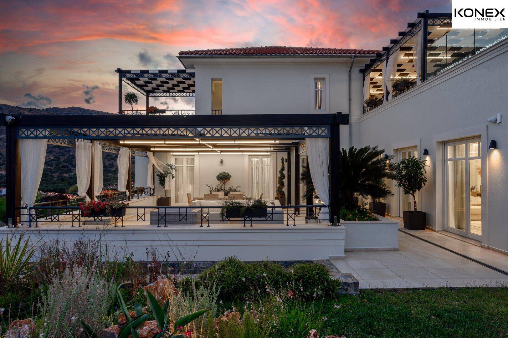 Abendliche Ansicht der Villa mit beleuchteter Terrasse und gepflegtem Gartenbereich.