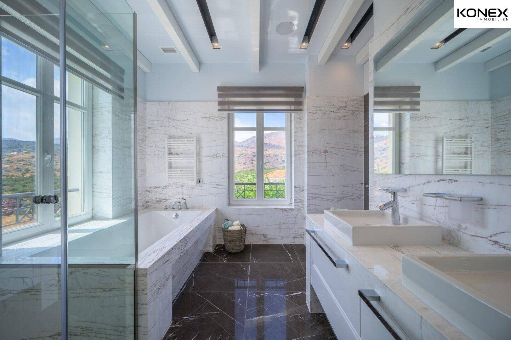 Luxuriöses Badezimmer mit Marmorfliesen, Doppelwaschbecken und Badewanne mit Bergblick.