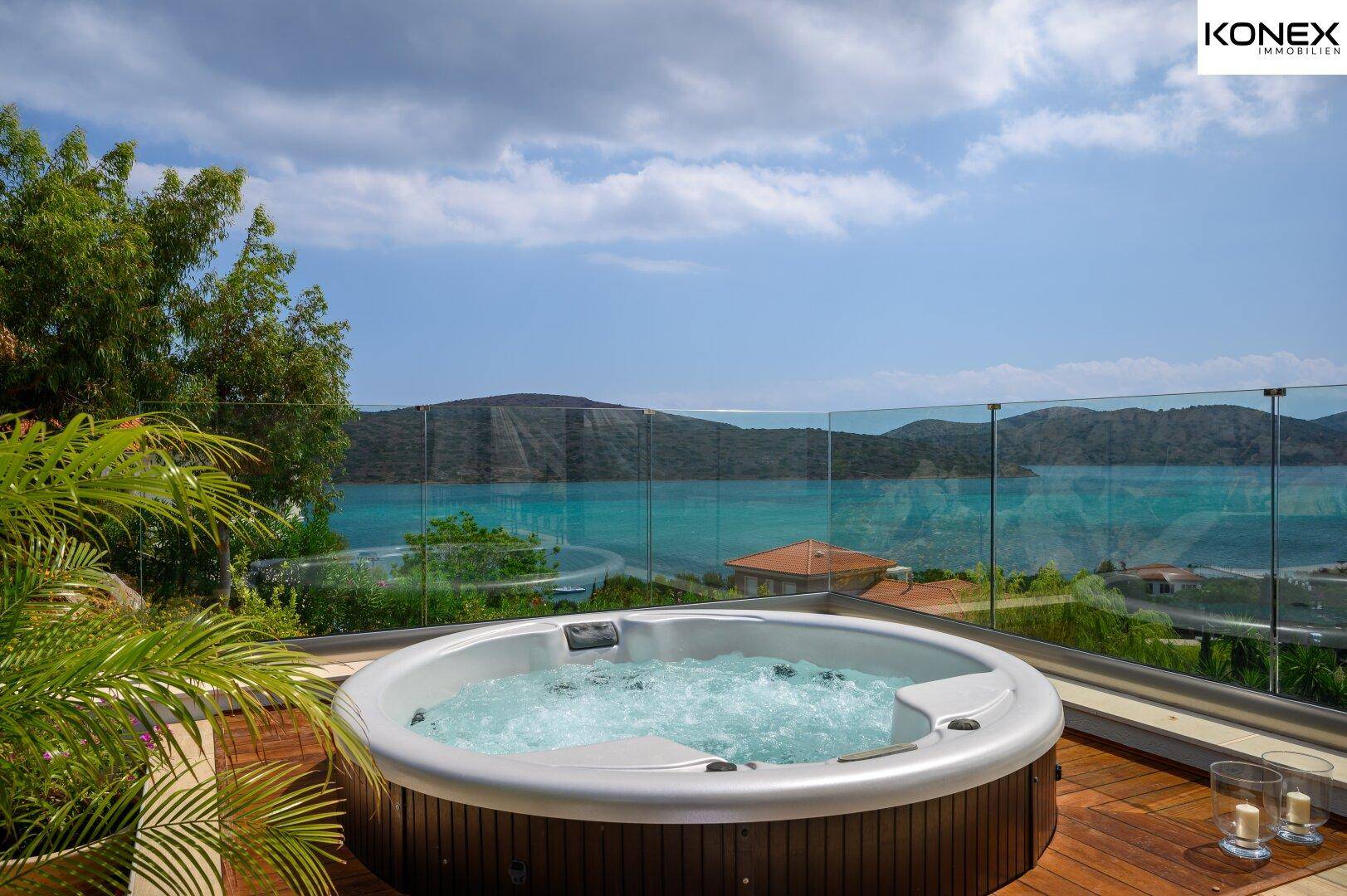 Whirlpool auf einer Terrasse mit Glasgeländer und atemberaubendem Meerblick.
